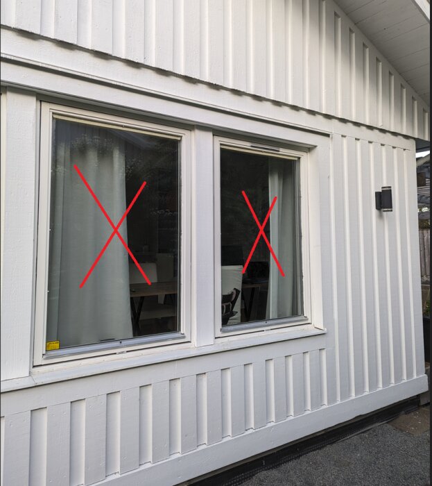Två fönster på en vit vägg, varje fönster är överkryssat med ett rött "X".