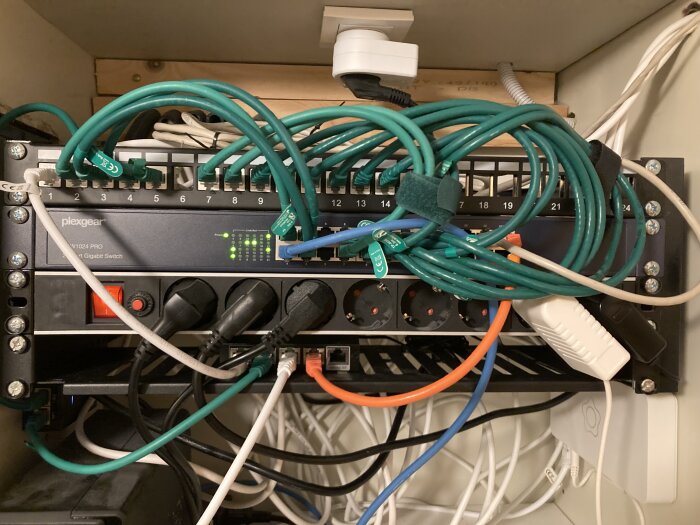 En nätverksswitch med många anslutna Ethernet-kablar och strömkablar, oorganiserad kabelhantering, teknisk infrastruktur.