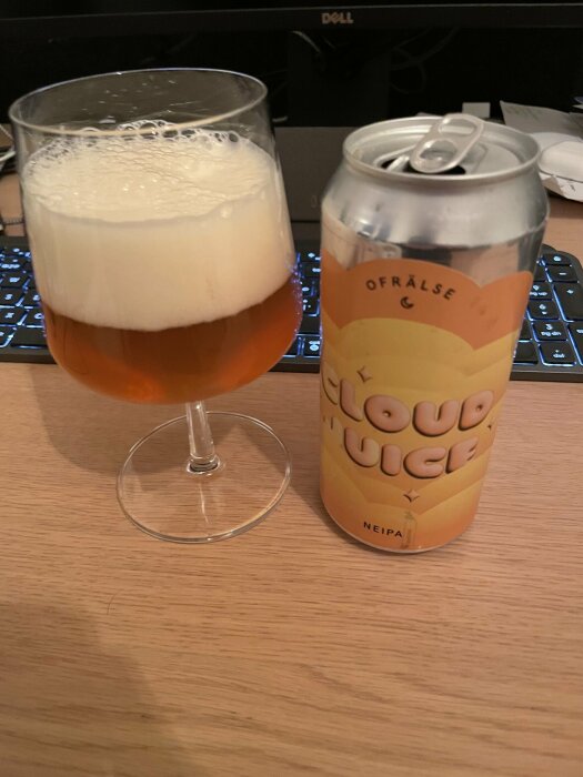 Ett glas med öl och en burk NEIPA, kallad "Cloud Juicer", på ett skrivbord.