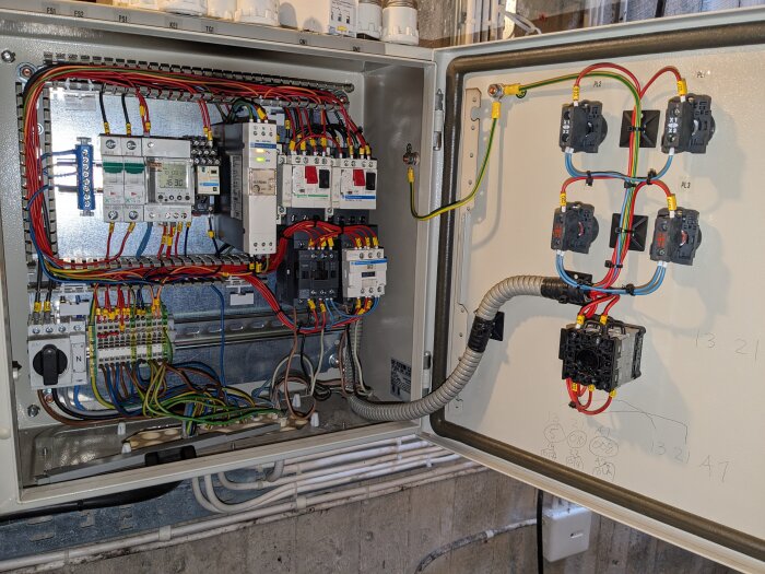 Elektriskt skåp med ordnat kablage, reläer, brytare och säkringar för industriell eller kommersiell användning.
