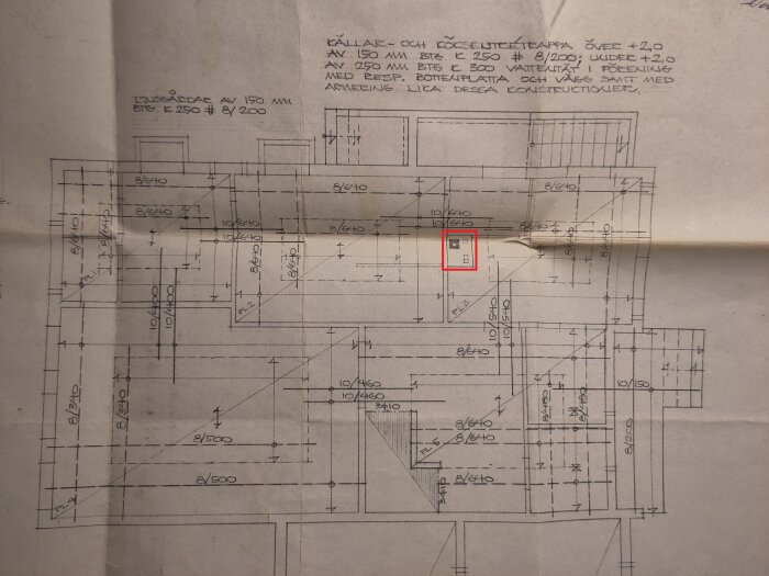 Arkitektonisk ritning, vikta sidor, tekniska märkningar, dimensioner, röd markerad detalj, konstruktionsplan.