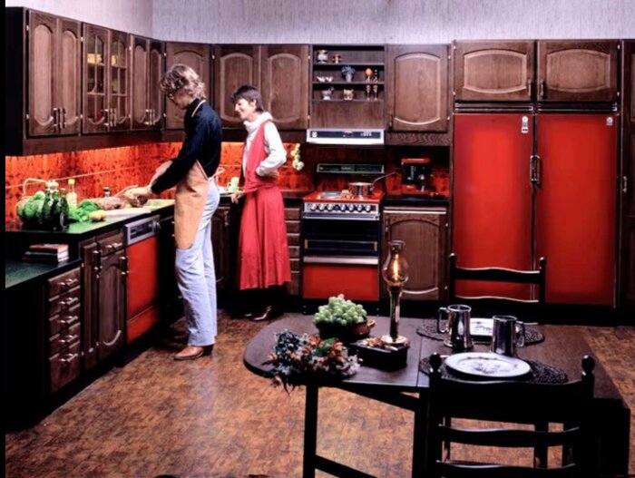 Två personer lagar mat tillsammans i ett rött och brunt vintagekök.