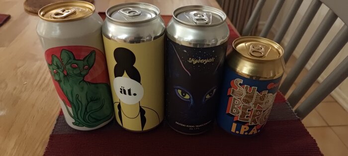 Fyra ölburkar med olika konstnärliga designer på ett bord med en röd bordstablett.