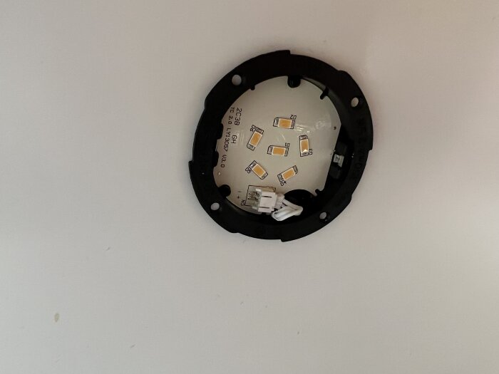 Öppen LED-lampa utan kåpa, elektronik synlig, monterad på vit vägg.