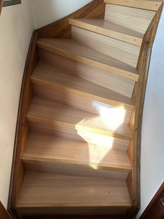 Trappa av trä med solljus som skapar skuggor på trappstegen.