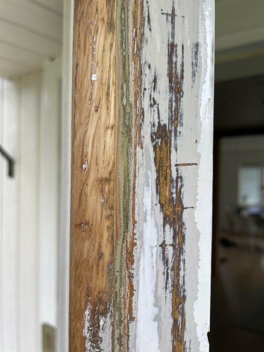 Slitet trä och färg på en dörr- eller fönsterkarm. Behov av underhåll eller renovering synligt.
