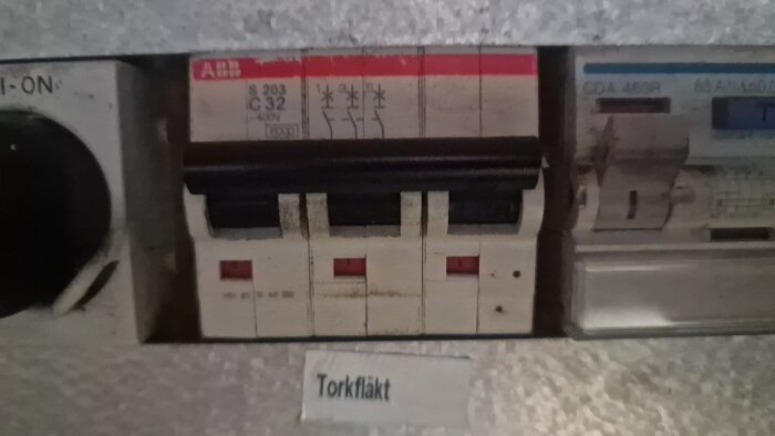 Elskåp med säkringar, etikett "Torkfläkt", ABB-märke, grått, installationsutrustning, strömbrytare.