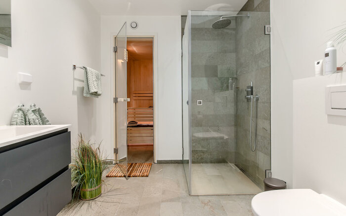 Modernt badrum med dusch, handfat, spegel och bastu.