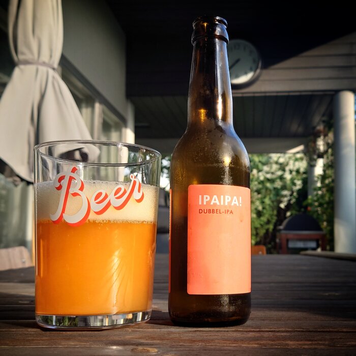 Ölglas delvis fyllt, IPA-flaska, terrass, skymning, avslappnat, fritid, utomhus, sommartid, avkoppling.