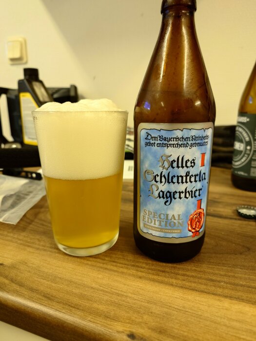 Ölglas med mycket skum bredvid en ölflaska på ett bord. "Special edition", bryggeri logo synlig.