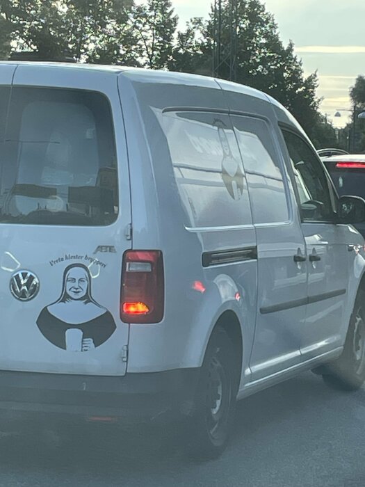 Vit Volkswagen transportbil med klistermärke av en icke identifierbar person klädd som nunna som håller en ölsejdel.