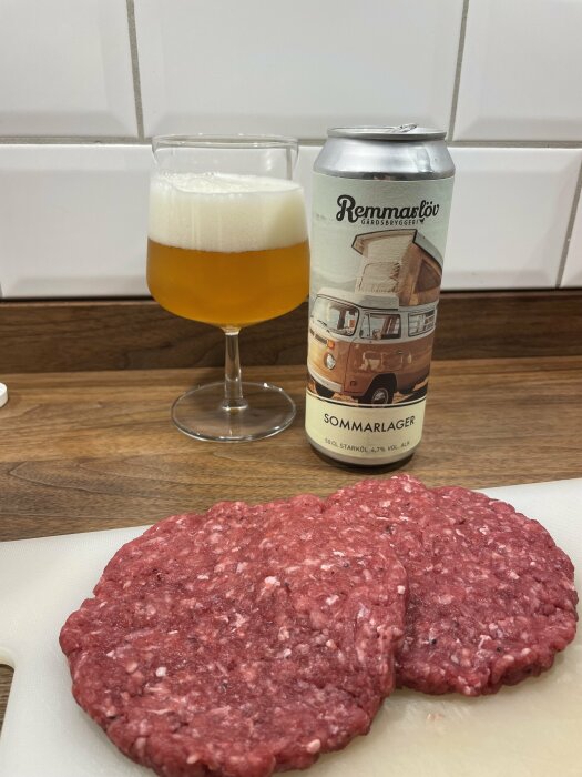 Öl i glas, burk, två råa hamburgare på skärbräda, hemmiljö, kök.