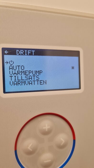 LCD-display med menyalternativ "AUTO", "VÄRMEPUMP", "TILLSATS", "VARMVATTEN", och fysiska knappar i förgrunden.