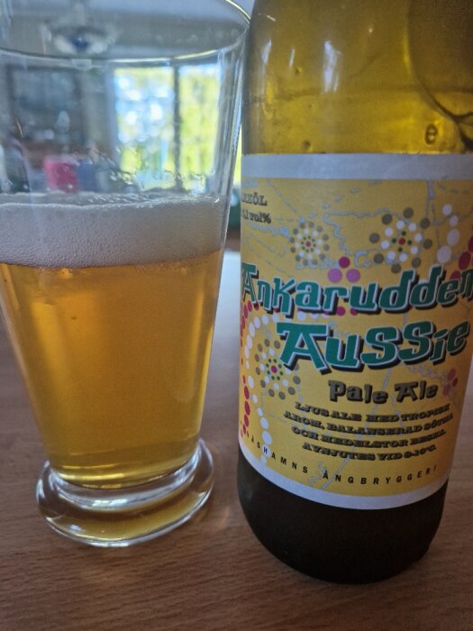 Ett glas öl bredvid en etikettmärkt flaska "Aussie Pale Ale".