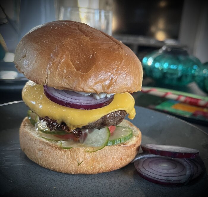 Saftig hamburger med smält ost, sallad, lök och pickles i ett glänsande briochebröd.