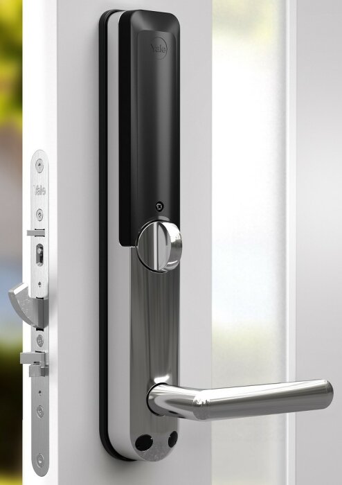 Moderna digitala dörrlåset på en vit dörr, märke Yale, med handtag och låsmekanism.