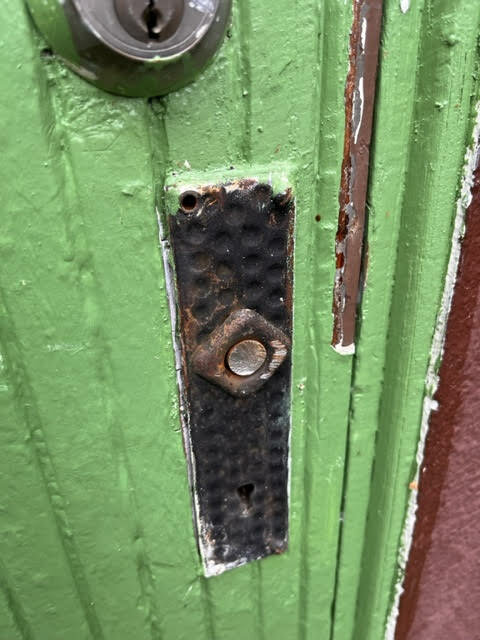 Sliten grön dörr, gammal, rostig dörrkikare, repor, skadad färg, säkerhet, privatliv.