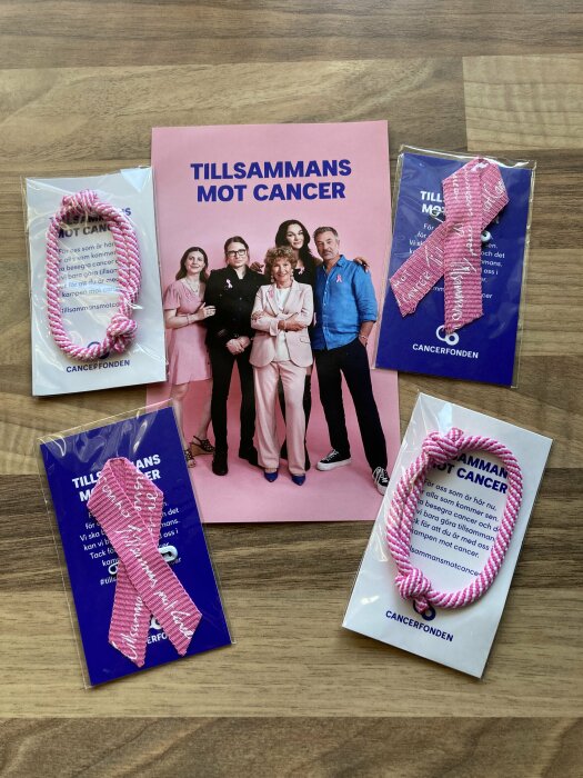 Kampanjmaterial för cancermedvetenhet med rosa band, broschyr och grupp människor som stöder orsaken.