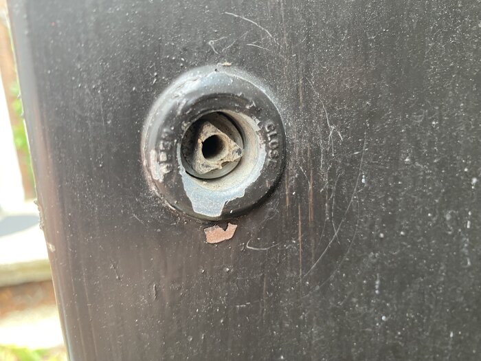 Svart yta, skadat lås eller handtag, repor, utan synlig nyckel eller handtag, närbild, fysisk skada.