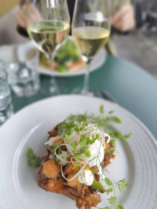 Gourmeträtt, pocherat ägg, rostat bröd, kaviar, örter, vita vinglas, oskarp bakgrund, restaurangmiljö.