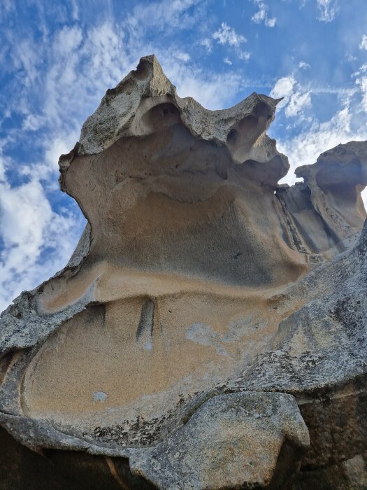 Erosionsformade klippor mot en blå himmel med vita moln.