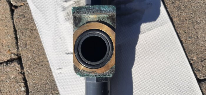 Ett närbildsfoto av en grön och brun metallkomponent, förmodligen en del av en maskin eller ett rörsystem.