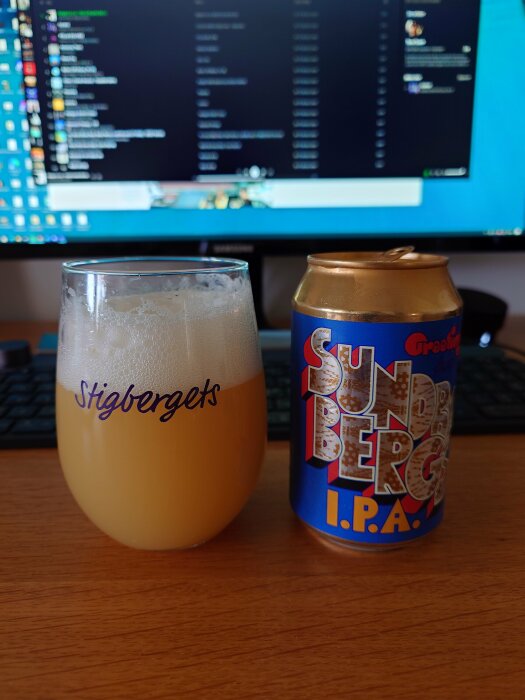 Ett ölglas med skum och en Burk IPA framför en datorskärm som visar kod och chatt.