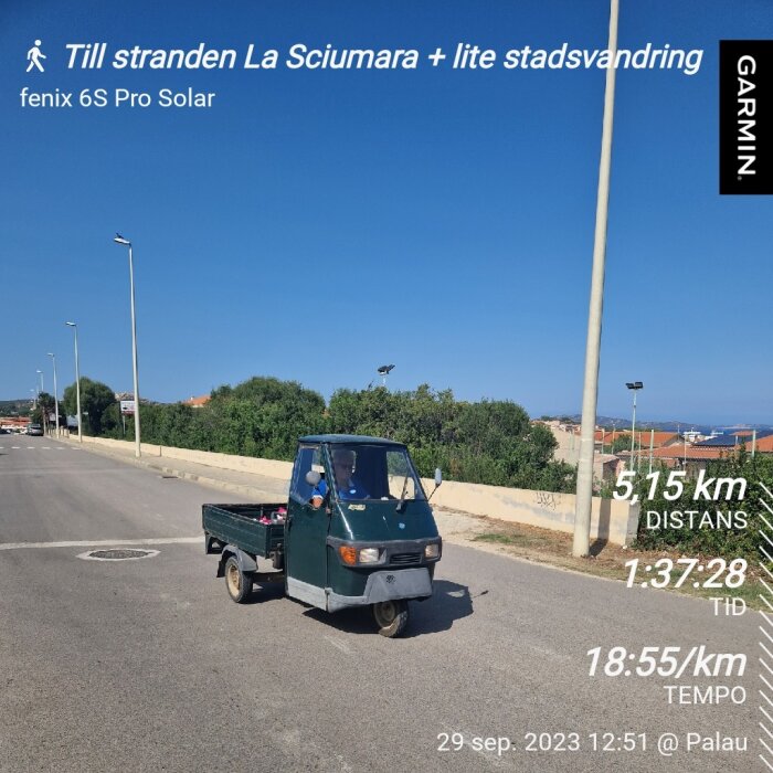 En liten lastbil på gata, klarblå himmel, skyltar med promenaddetaljer, datum och tid.