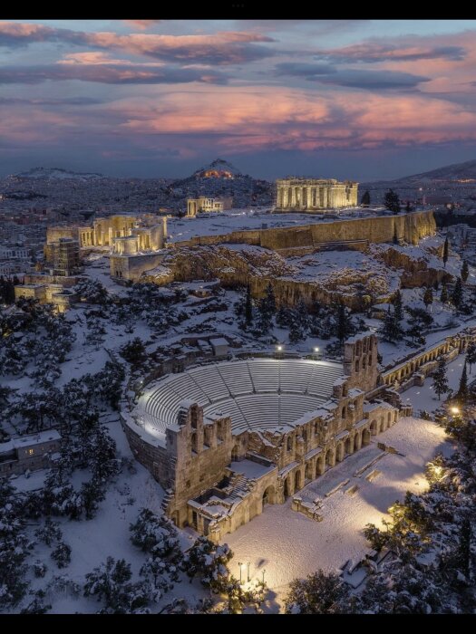 Athen täckt av snö vid solnedgången. Akropolis och Herodes Atticus Odeon synliga. Antik arkitektur, vinterscen.