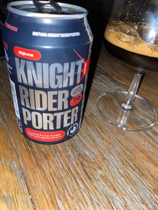 Ölburk med texten "Knight Rider Porter" bredvid ett delvis fyllt glas på träbord.