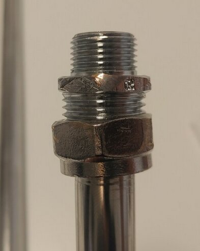 En metallpipa med gängor och en sexkantig mutter, tätad anslutning, teknisk, industriell komponent, närbild.