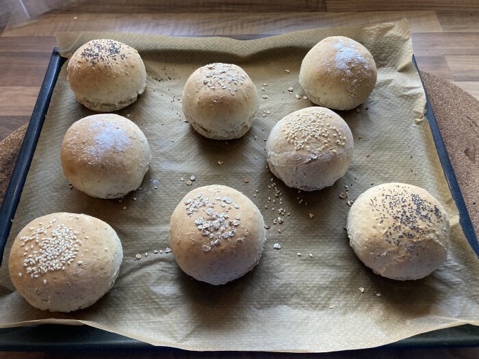 Nybakte rundstykker på stekebrett, noen med sesam- og valmuefrø, på kjøkkenbenk.