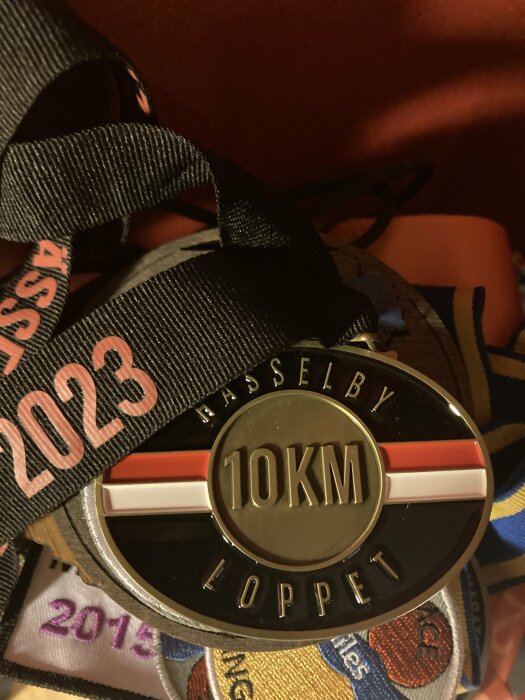 Medalj för ett 10 km-lopp, märkt "Vasaloppet 2023", flera loppband i bakgrunden.
