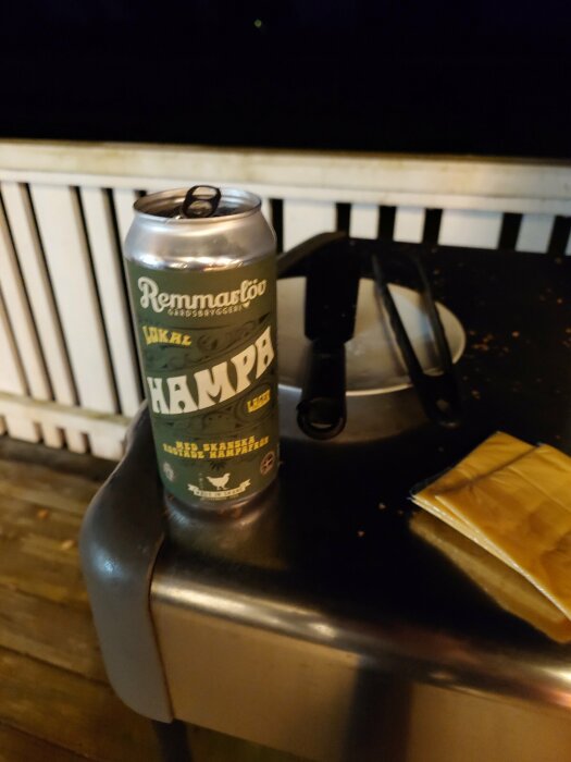 En ölburk och solglasögon på ett bord utomhus nattetid. Verkar avslappnat eller efter en fest.