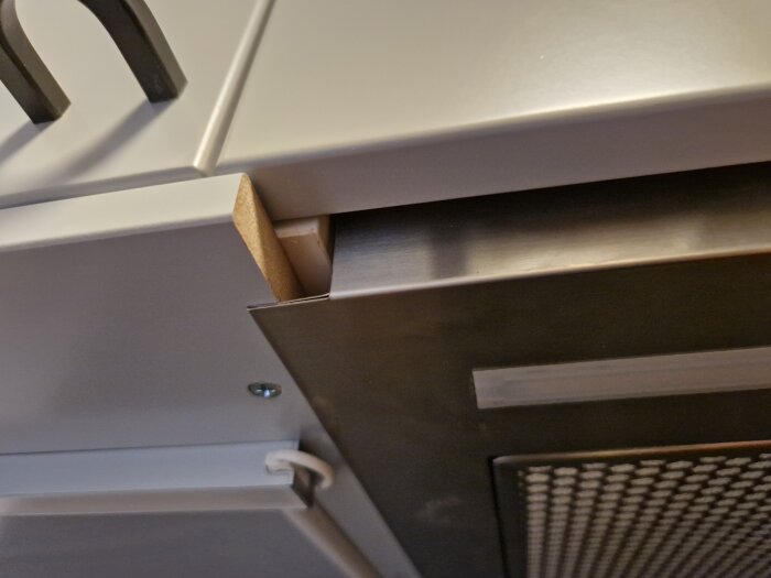 En öppen grå kökslåda med en synlig kartongbit och delar av ett skåp ovanför.
