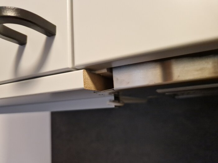 En kökslåda delvis öppen visar handtag, kökslucka och skarven av en bänkskiva.