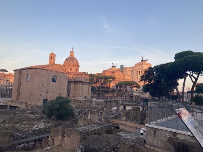 Romerska ruiner, barockkyrkor, Altare della Patria, träd, kvällsljus, historisk stadssilhuett, arkeologisk plats, mjuk himmel.