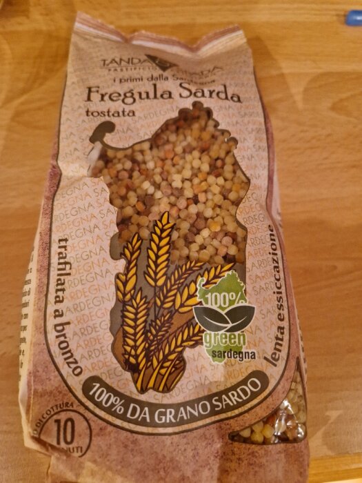 Förpackning med Fregula Sarda-pasta, små kulörta kulor, etikett anger 100% sardinskt vete, 10 minuters koktid.