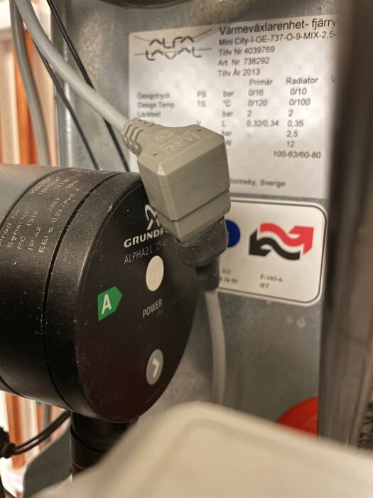 En värmepump ansluten till el, etikett för Alfa Laval enhet, tekniska specifikationer, strömbrytare på.