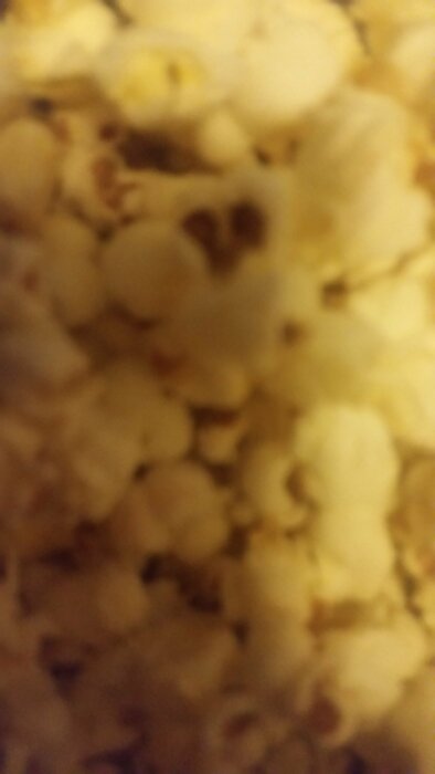 Bilden är suddig, visar tätt packade, ljusgula föremål som troligtvis är popcorn. Närbild, inga tydliga detaljer syns.