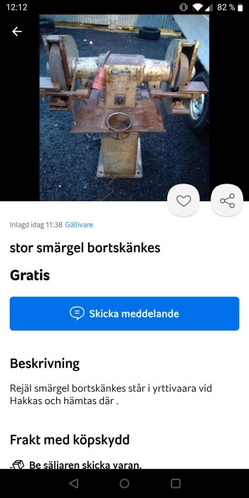 Använd bänkslipmaskin, rostig, med två slipstenar, erbjuds gratis. Bakgrund asfalt och däck, mobilskärmskapning.