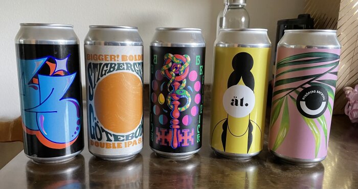 Färgglada ölburkar med olika designer radade på en yta.