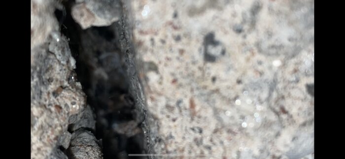 Sprucken betongyta med suddig bakgrund och synlig textur. Fokus på klyfta.