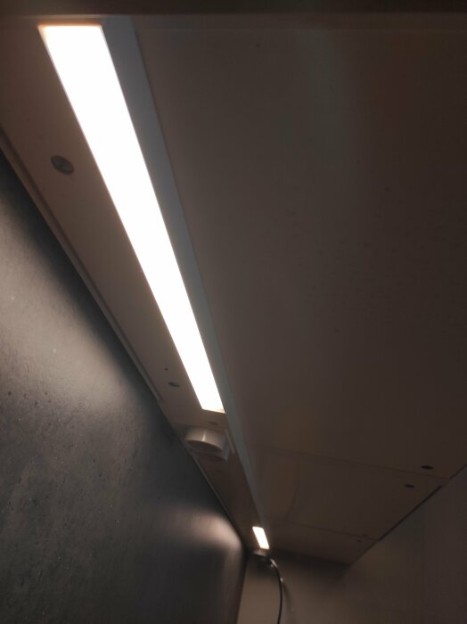 Fluorescent taklampa, kablar, mörkt utrymme, takpaneler, suddig förgrund, belysning, inomhusmiljö, dunkelt, otydligt.