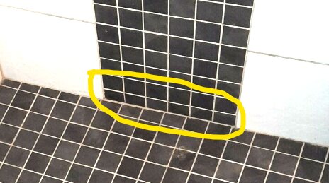 Golv med svarta och vita kakelplattor, markerad del med gult, smuts eller fläck inne i ringen.