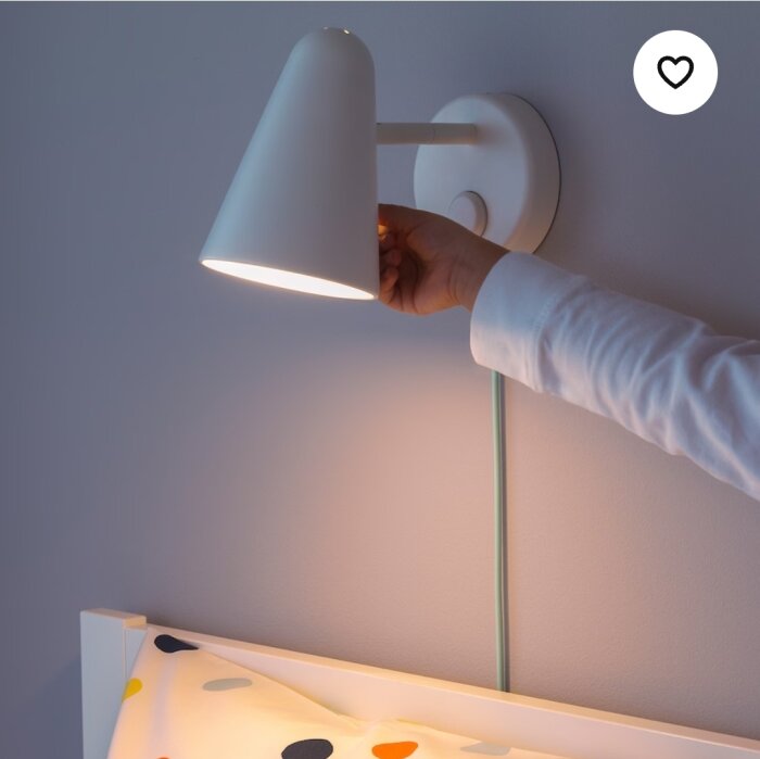 Vit vägglampa, person justerar, tänd, sänggavel, hjärtikon, minimalistisk design, heminredning.