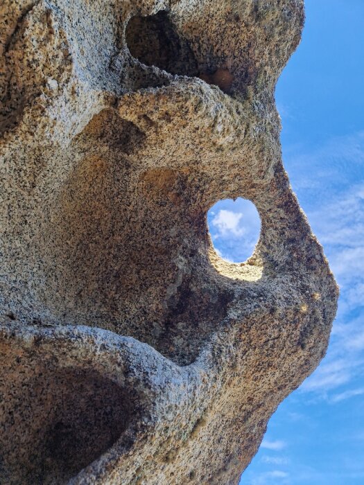 Erosionsformade hål i klippa med himmel i bakgrunden. Naturligt konstverk.