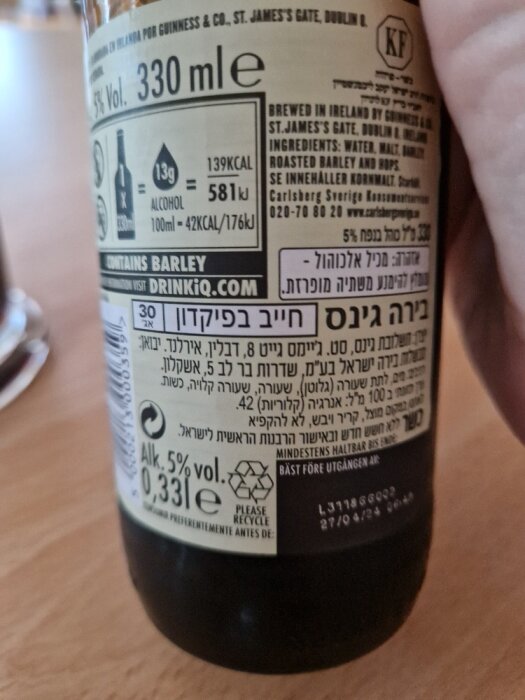 Ölflaska etikett, näringsinformation, ingredienser, återvinningsinfo, flerspråkig text, innehåller korn.