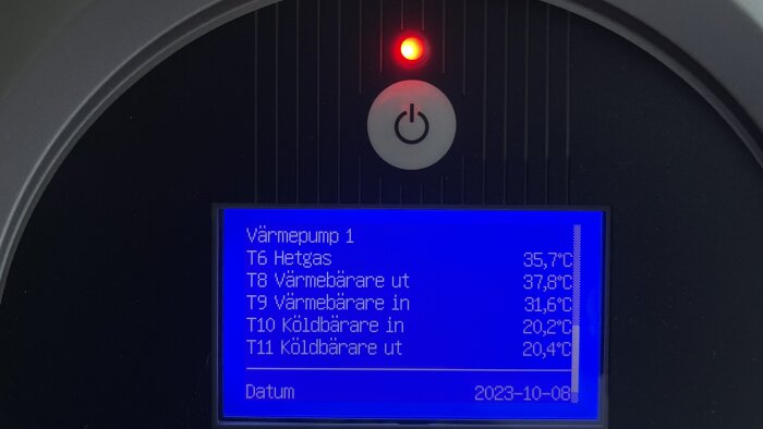 Display visar temperaturer för värmepump, med påslaget ljus och strömbrytare, datum noterat.