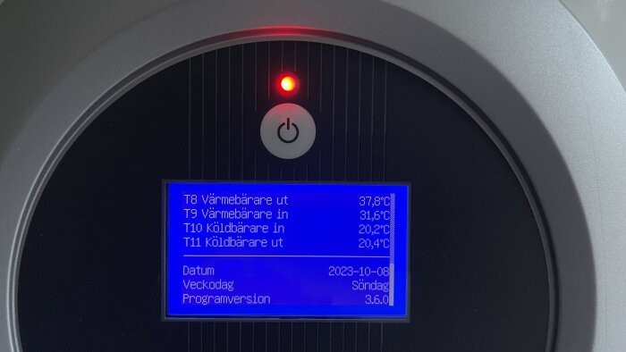 Ett digitalt display visar temperaturdata och datum, omgiven av svart och grå ram.